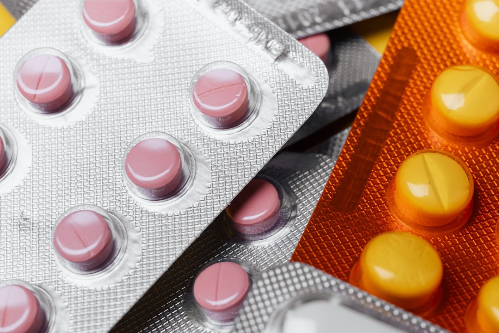Blister packs of pink and yellow tablets seen up close